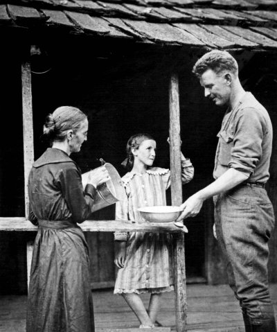 Photo of Sergeant Alvin C. York after his return to his Tennessee home. York's mother is pouring water into the basin and his younger sister is standing on the cabin's back porch. York turned down many lucrative offers, including one worth $30,000 to appear in vaudeville, to return to the life he had known before the war.